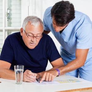 male-nurse-helping-senior-man-in-solving-puzzle